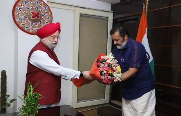 Hardeep Singh Puri presenting a bouquet of flowers to Suresh Gopi as he takes charge at the Ministry of Petroleum and Natural Gas