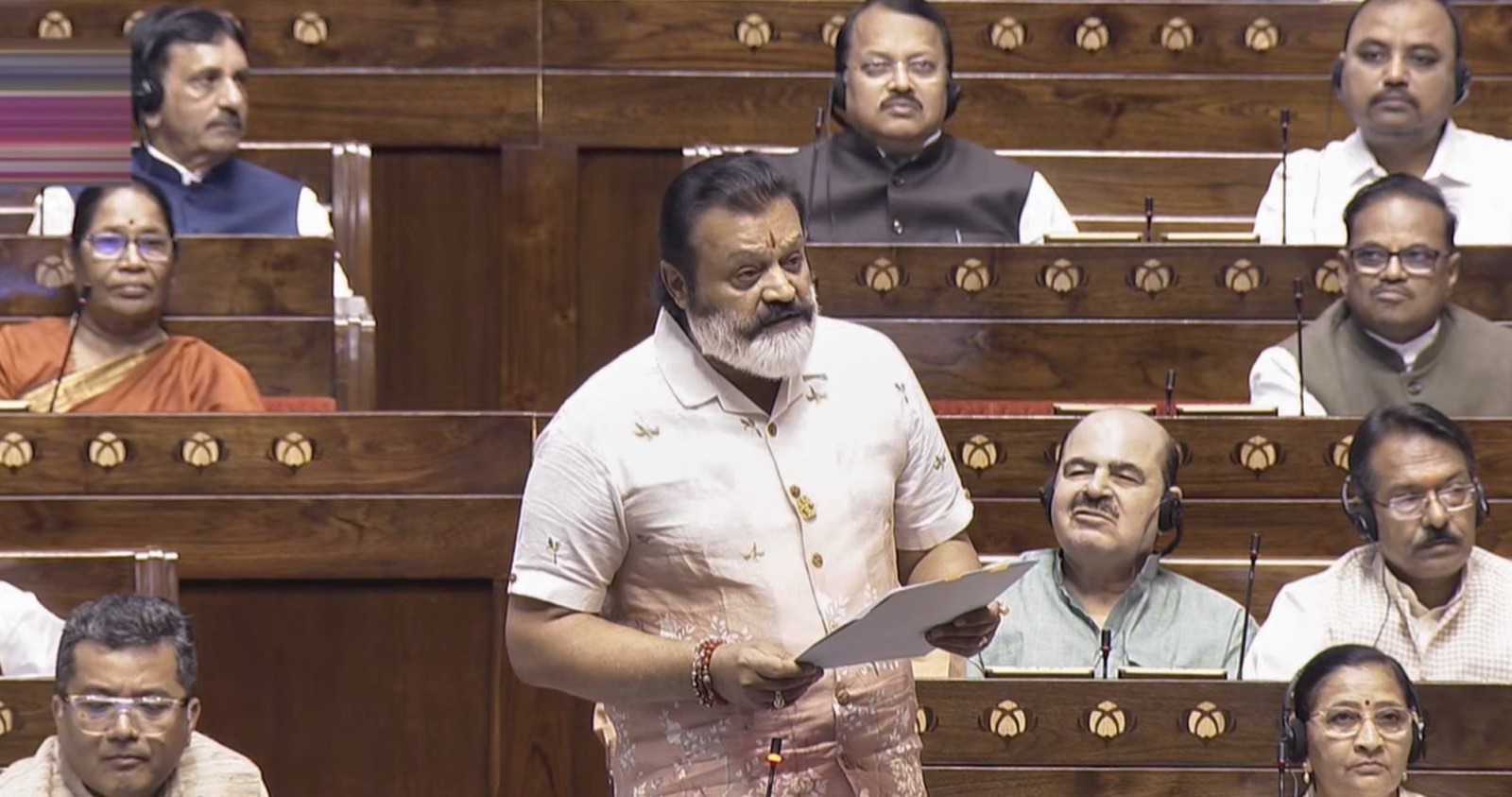 Suresh Gopi standing and reading from a paper while addressing the House in the Parliament of India chamber